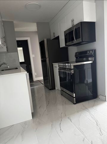 Edmonton apartment for rent - A modern kitchen with black appliances and white cabinets.
