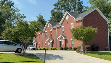 Orangeburg apartment for rent - A red brick building with a white car parked in front.
