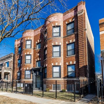 Chicago apartment for rent - A red brick building with black iron fencing in front.