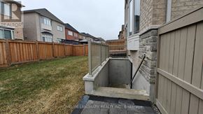 Vaughan (Vellore Village) apartment for rent - A backyard with a wooden fence and a stone wall.