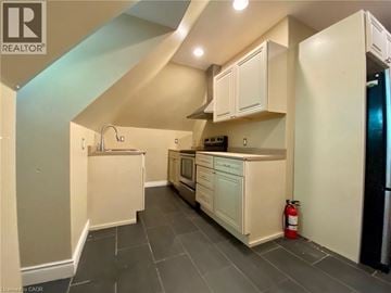 London apartment for rent - A kitchen with white cabinets and a black fridge.