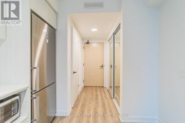 Vaughan (Vaughan Corporate Centre) condo for rent - A kitchen with a refrigerator and microwave on the left and a hallway on the right.
