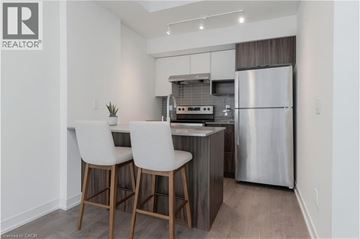 Burlington townhouse for rent - A modern kitchen with white chairs and a stainless steel refrigerator.