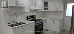 Clarington (Bowmanville) apartment for rent - A kitchen with white cabinets and a black stove top oven.