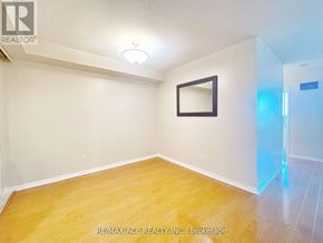 Toronto (Woburn) condo for rent - A room with a wooden floor and a white wall with a picture frame.