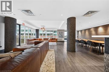 Kitchener condo for rent - A modern living room with a brown leather couch and a wooden floor.