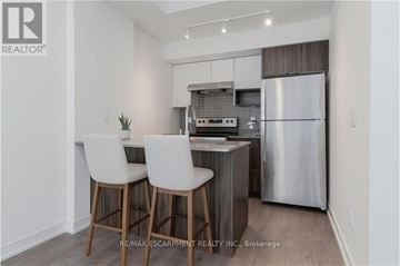 Burlington (Lasalle) townhouse for rent - A modern kitchen with white chairs and a stainless steel refrigerator.