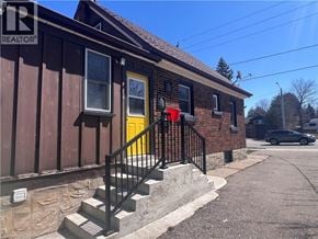 Kitchener apartment for rent - A house with a yellow door and a black railing on the stairs.