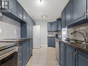 Ajax (Central West) condo for rent - A kitchen with dark blue cabinets and a white refrigerator.