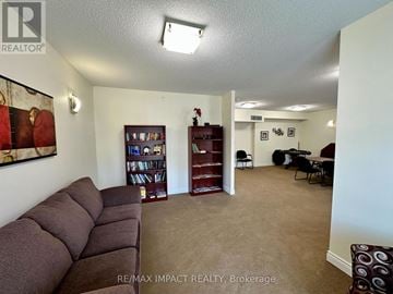 Clarington (Bowmanville) condo for rent - A living room with a brown sofa and a bookshelf.