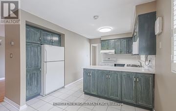 Toronto (Rouge) apartment for rent - A kitchen with a white refrigerator and green cabinets.