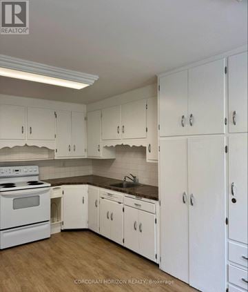 Kitchener apartment for rent - A kitchen with white cabinets and a stove top oven.