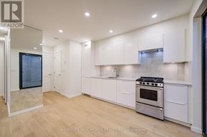 Toronto (Little Portugal) multi-family for rent - A modern kitchen with white cabinets and a stainless steel stove.