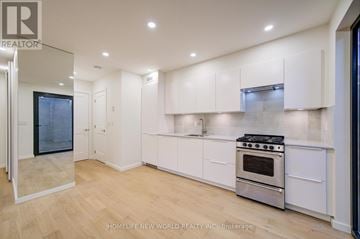 Toronto (Little Portugal) multi-family for rent - A modern kitchen with white cabinets and a stainless steel stove.