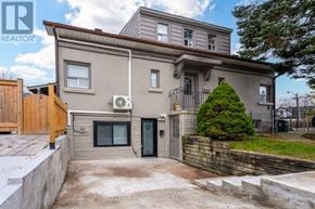 Toronto (Long Branch) fourplex for rent - A house with a grey exterior and a green tree in front.