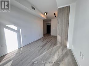 Toronto (Centennial Scarborough) condo for rent - A room with wooden flooring and a white wall with a doorway leading to another room.