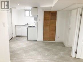 Toronto (Oakridge) apartment for rent - A realtor photo of a kitchen with white cabinets and a wooden door.