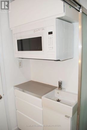 Toronto (Oakridge) apartment for rent - A white microwave oven is mounted above a white sink in a small kitchen.