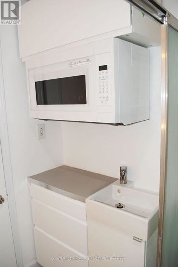 Toronto (Oakridge) apartment for rent - A white microwave oven is mounted above a white sink in a small kitchen.