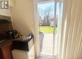 Markham (Thornlea) apartment for rent - A kitchen with a microwave on the counter and a view of a backyard through the glass door.
