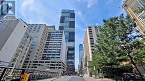 Toronto (Bay Street Corridor) condo for rent - A city street with tall buildings on either side and a clear blue sky above.