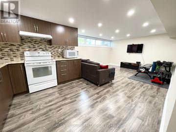 Toronto (Willowridge-Martingrove-Richview) apartment for rent - A well-lit kitchen with a white stove and microwave, wooden cabinets, and a grey floor.