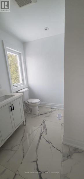 Toronto (Highland Creek) apartment for rent - A bathroom with a toilet, sink, and a window.
