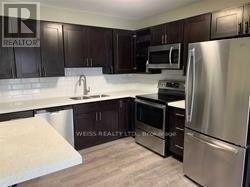 Toronto (Yorkdale-Glen Park) apartment for rent - A kitchen with dark wood cabinets and stainless steel appliances.