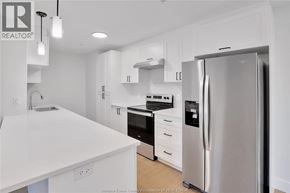 Lasalle condo for rent - A modern kitchen with white appliances and cabinets.