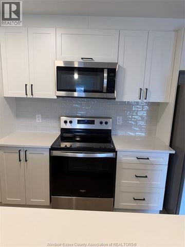 Lasalle condo for rent - A kitchen with white cabinets and a black stove top oven.