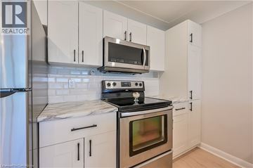 Hamilton apartment for rent - A kitchen with white cabinets and a black stove top.