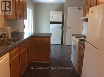 St. Catharines (Secord Woods) apartment for rent - A kitchen with wooden cabinets and a white fridge.