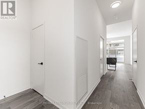 Toronto (South Parkdale) condo for rent - A hallway with a door on the left and a table with chairs on the right.