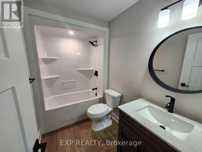 North Grenville multi-family for rent - A bathroom with a toilet, sink, and a shower with a glass door.