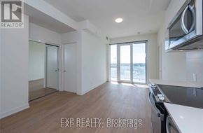 Toronto (Parkwoods-Donalda) condo for rent - A well-lit, empty kitchen and living room with wooden floors and white walls.