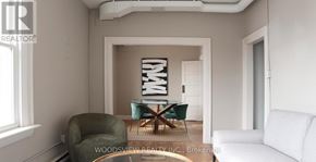Oshawa (O'neill) apartment for rent - A living room with a green armchair, a white sofa, and a coffee table.