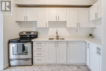 Orangeville condo for rent - A white kitchen with a black stove top oven and a silver oven underneath.