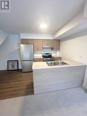 Whitby (Downtown Whitby) townhouse for rent - A modern kitchen with a refrigerator, sink, and cabinets.