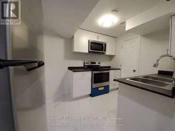 Newmarket (Stonehaven-Wyndham) apartment for rent - A small kitchen with white cabinets and a black fridge.