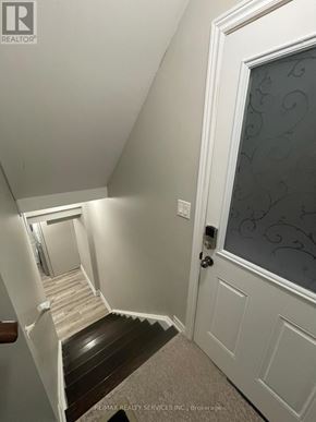 Brampton (Credit Valley) apartment for rent - A hallway with a staircase leading to a door with a glass window.