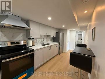 Ottawa townhouse for rent - A modern kitchen with a black stove top oven and white cabinets.