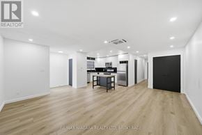 Pelham (Fonthill) duplex for rent - A spacious room with wooden flooring and white walls, featuring a kitchenette with a sink, stove, and refrigerator.