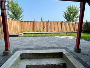 Whitchurch-Stouffville (Stouffville) apartment for rent - A backyard with a wooden fence and a concrete fire pit.