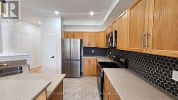 Richmond Hill (Oak Ridges) apartment for rent - A kitchen with wooden cabinets and a black and white tile backsplash.