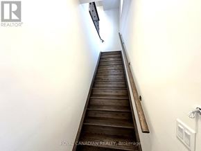 Barrie multi-family for rent - A long flight of wooden stairs with a white wall on the side.