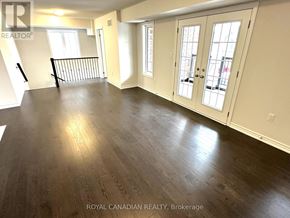 Barrie multi-family for rent - A spacious room with wood flooring and white walls.