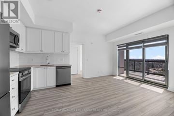Clarington (Bowmanville) condo for rent - A spacious kitchen with white cabinets and a view of the city through the windows.