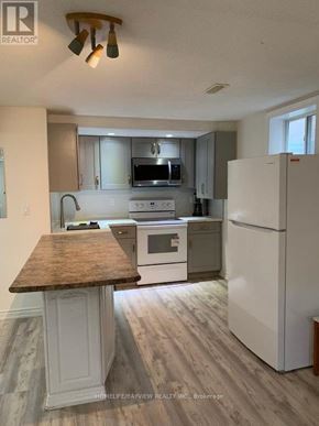 Richmond Hill (Harding) apartment for rent - A kitchen with a white refrigerator, white cabinets, and a wooden island.