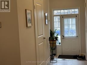 Brantford townhouse for rent - A hallway with a plant on a stand and a door on the right.
