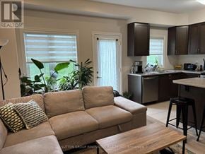 Brantford townhouse for rent - A living room with a couch, a coffee table, and a kitchen area in the background.